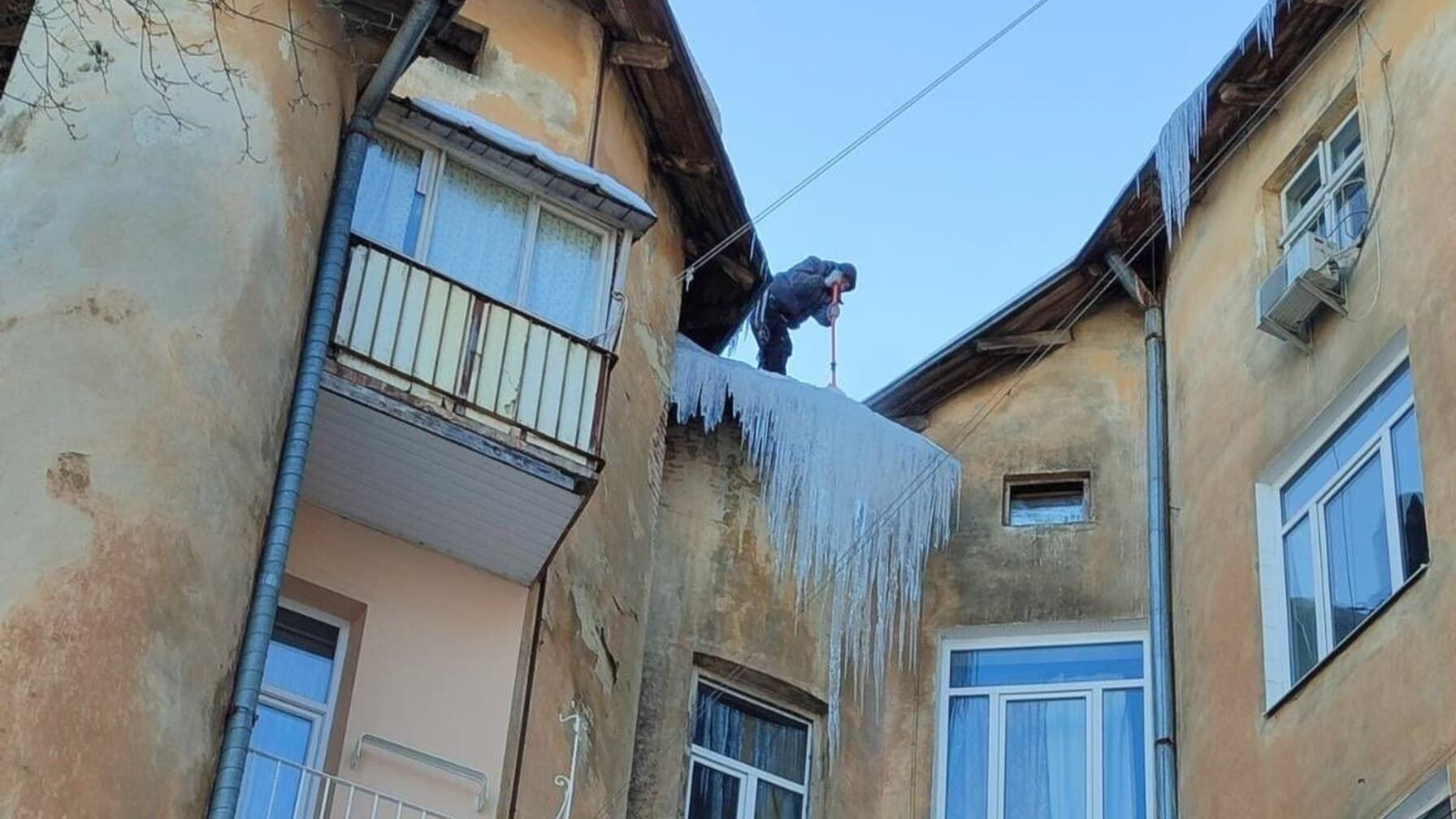 альпініст збиває бурулі з даху у львові/ фото: лмр