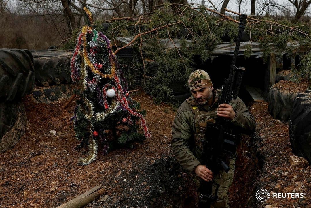 Фото умовне / Військовослужбовець зі зброєю в руках біля прикрашеної ялинки в окопах на передовій / Clodagh Kilcoyne