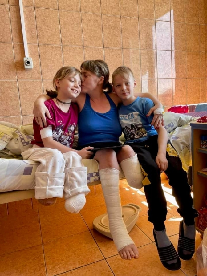 A boy takes care of his mother and sister who lost their legs after the missile attack in Kramatorsk